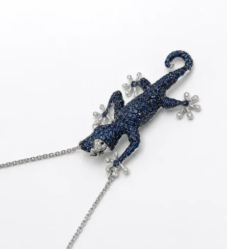 Scopri la nostra raffinata collana a forma di geco in oro bianco 18kt, impreziosita da intensi zaffiri naturali e luminosi diamanti. Un design unico per uno stile ricercato.