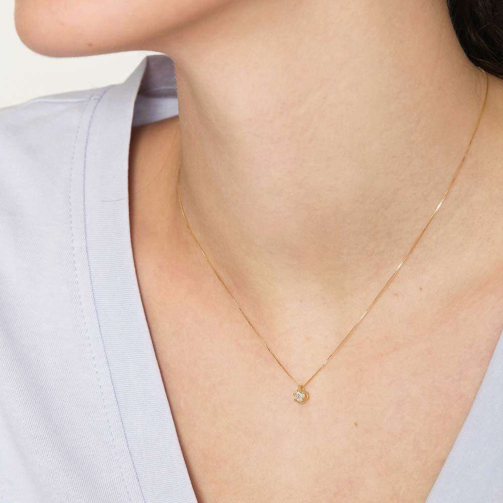 Collana sottile in oro giallo con piccolo pendente a punto luce indossata al collo