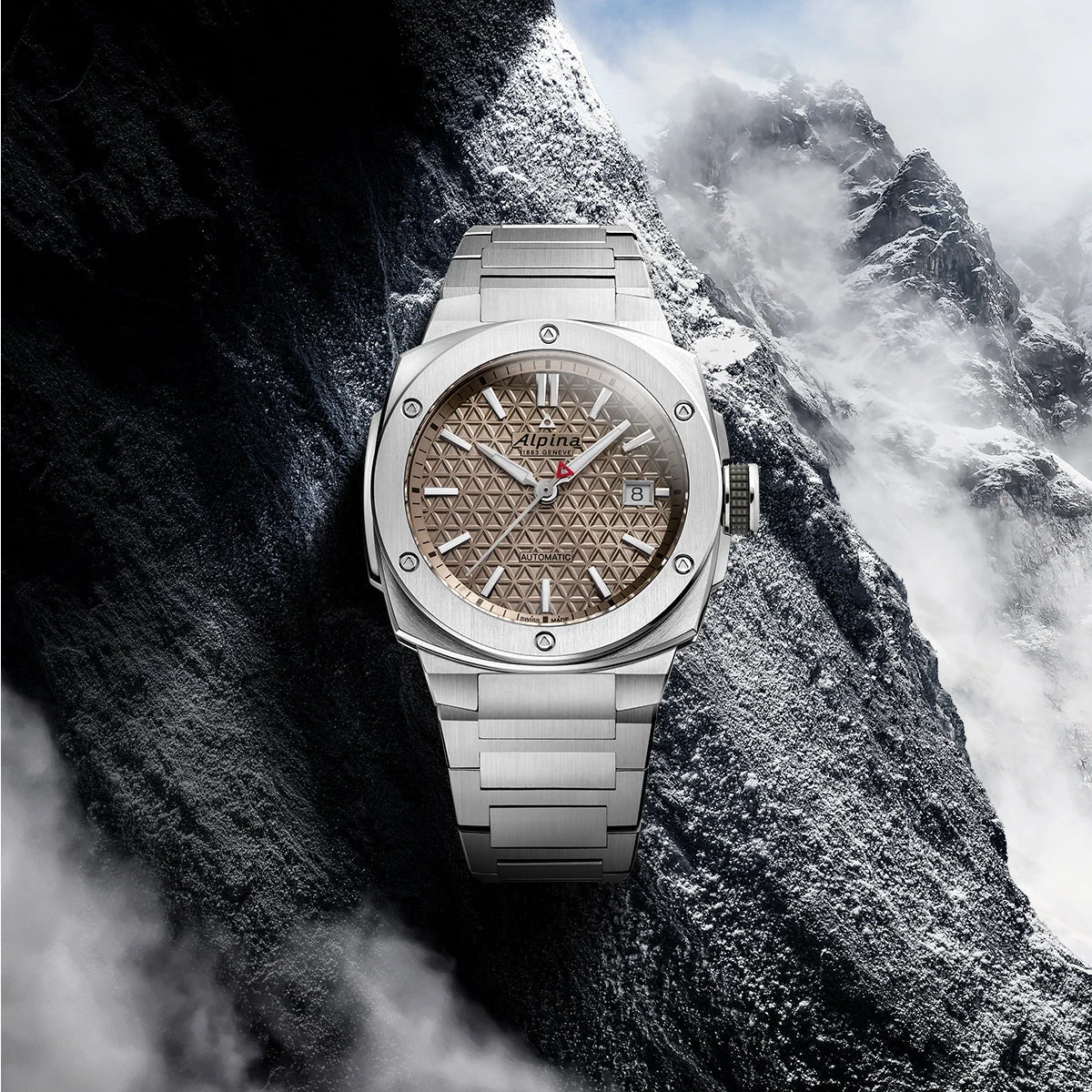 Orologio Alpina Alpiner Extreme in acciaio appoggiato sulla roccia, con le montagne sullo sfondo